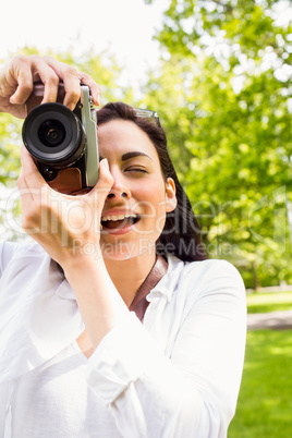 Beautiful brunette taking photo in the park