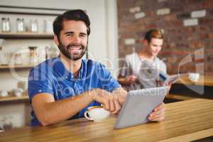 Young man having cup of coffee using tablet
