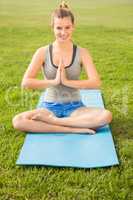 Smiling sporty blonde meditating on exercise mat