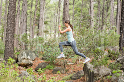 Young happy jogger jumping from a rock