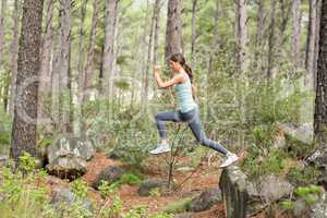 Young happy jogger jumping from a rock