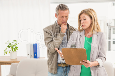 Casual business colleagues looking at clipboard