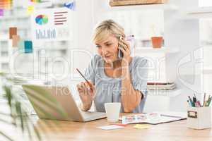 Businesswoman using laptop while on the phone