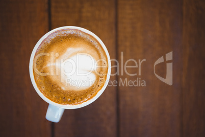 Cup of cappuccino with coffee art on wooden table