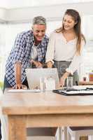 Smiling business colleagues using laptop