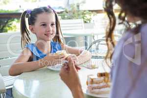 Mother and daughter enjoying cakes at cafe terrace