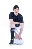 Kneeling rugby player holding a rugby ball