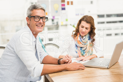 Smiling casual designer in front of his working colleague