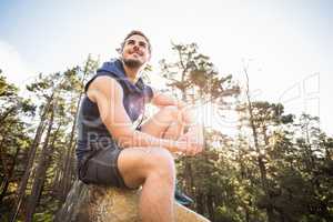 Young happy jogger sitting on rock and looking away