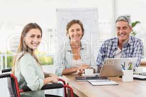 Casual businesswoman in wheelchair with colleagues