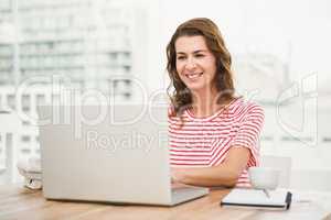 Smiling casual businesswoman using laptop