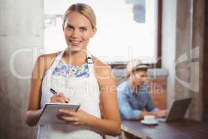 Smiling blonde waitress taking order in front of customer