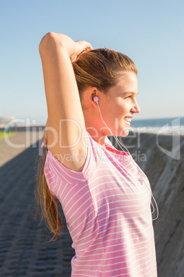 Smiling sporty blonde stretching and listening to music