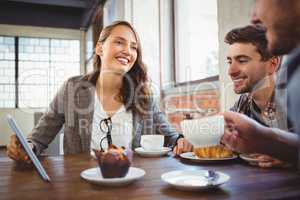 Smiling friends enjoying coffee and using at tablet