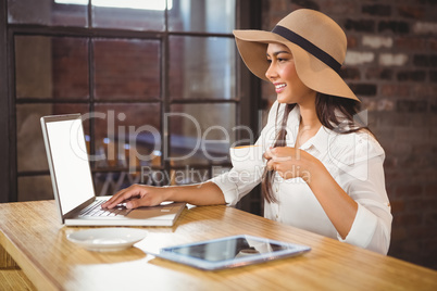 A businesswoman using her laptop while enjoying a coffee