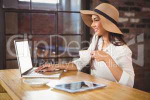 A businesswoman using her laptop while enjoying a coffee