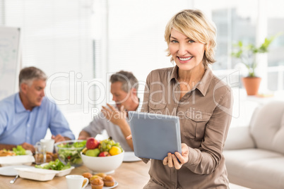 Smiling casual businesswoman using tablet at lunch