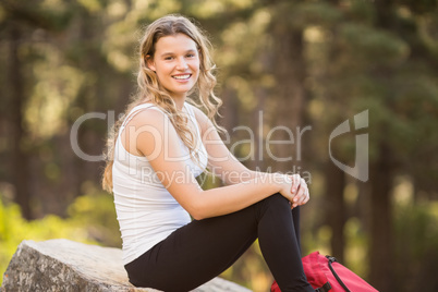 Young happy jogger sitting on rock and looking at camera