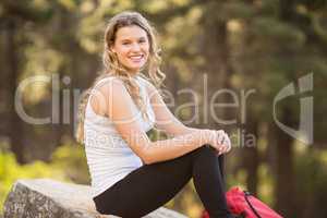 Young happy jogger sitting on rock and looking at camera