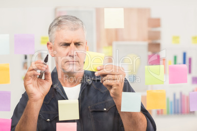 Casual businessman writing on post its