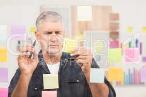 Casual businessman writing on post its
