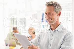 Smiling businessman scrolling on a tablet