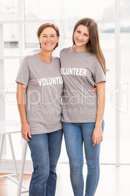 Smiling female volunteers putting arms around each other