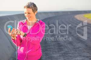 Smiling sporty woman enjoying music and holding phone