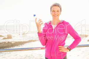 Smiling sporty woman with headphones holding bottle