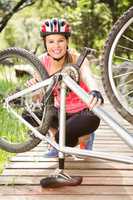Smiling blonde athlete checking her mountain bike