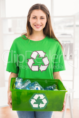 Smiling eco-minded brunette holding recycling box
