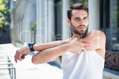 Focused handsome athlete stretching his arm
