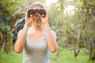 Smiling pretty brunette looking through binoculars