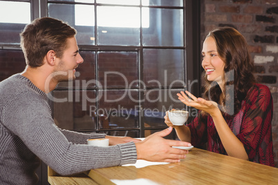 Smiling couple talking and drinking coffee