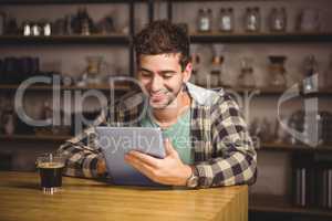 Smiling hipster having coffee and using tablet computer