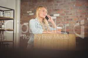 Pretty blonde phoning and holding take-away cup