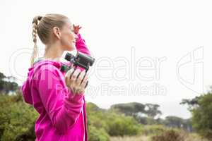 Female hiker looking away and holding binoculars