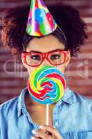 Portrait of a hipster with a party hat holding a lollipop