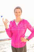 Smiling sporty woman with headphones holding bottle