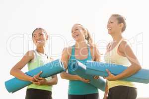 Laughing sporty women with exercise mats