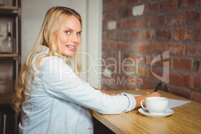 Smiling blonde writing on sheet of paper