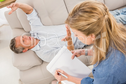 Depressed man lying on couch and talking to therapist