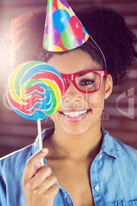 Portrait of a hipster hiding herself behind a lollipop