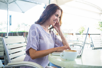 Woman enjoying a cappuccino using laptop