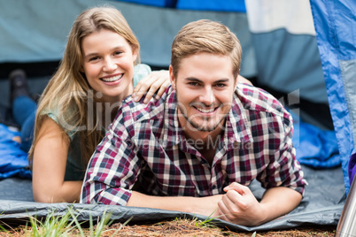 Portrait of a young happy couple lying in a tent