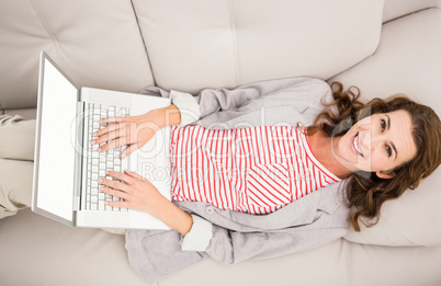 Smiling casual businesswoman relaxing on couch with laptop