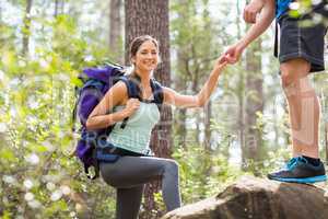 Happy hikers climbing on rock and smiling at camera