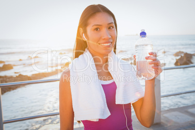 Smiling fit woman resting and holding water bottle