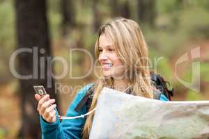 Young pretty hiker using compass and map
