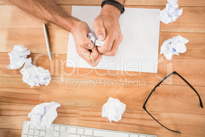 Hands crumpling paper on wooden desk